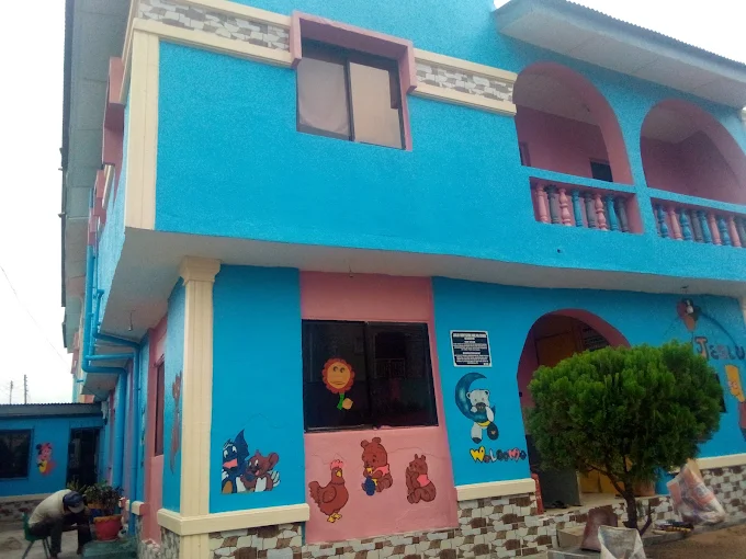 The school building painted blue and pink with cartoon murals along the ground floor